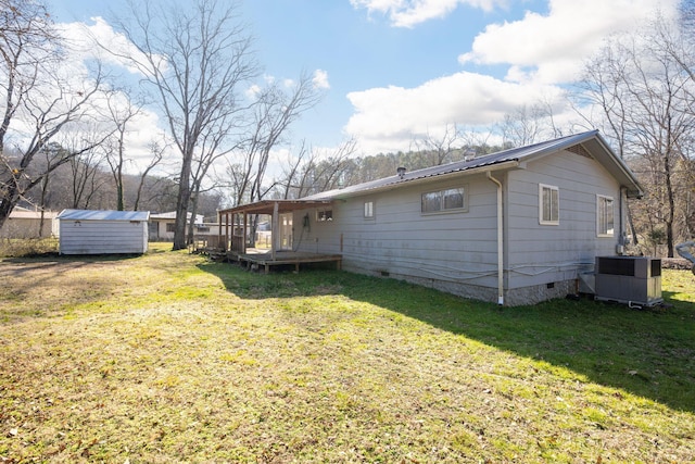 view of property exterior with a wooden deck, a yard, central AC, and a storage shed