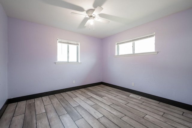 spare room with ceiling fan, a wealth of natural light, and light hardwood / wood-style floors