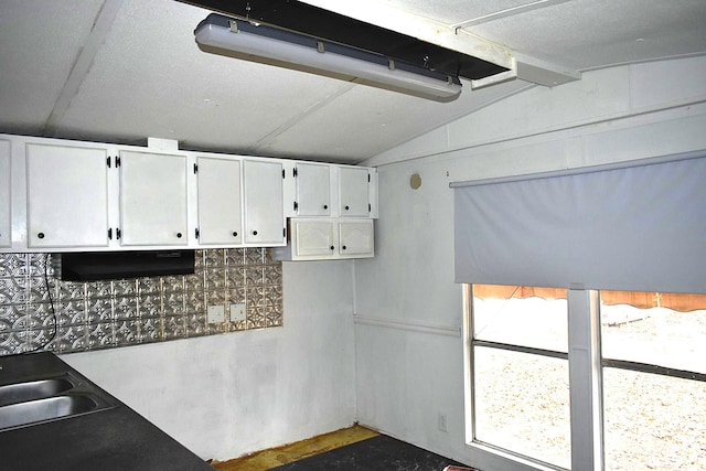 kitchen with white cabinetry, lofted ceiling, and sink