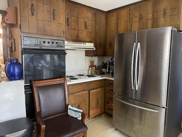 kitchen featuring white stovetop, black oven, and stainless steel refrigerator