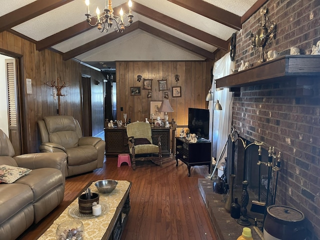 living room with dark wood-type flooring, wood walls, a chandelier, lofted ceiling with beams, and a brick fireplace