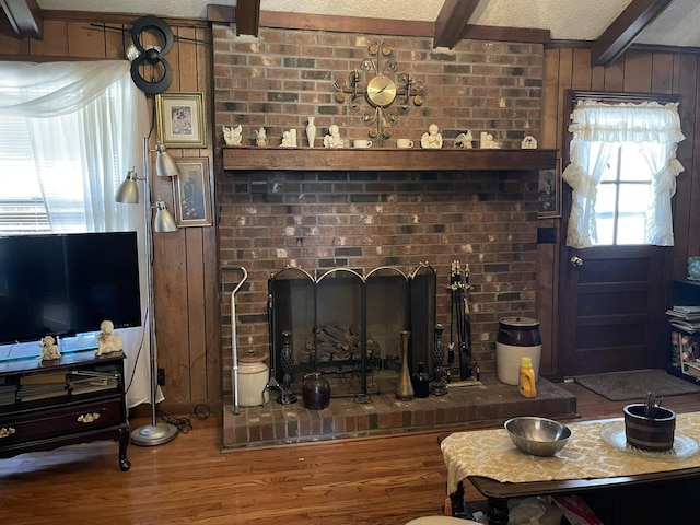 living room featuring beamed ceiling, a brick fireplace, hardwood / wood-style floors, and a textured ceiling