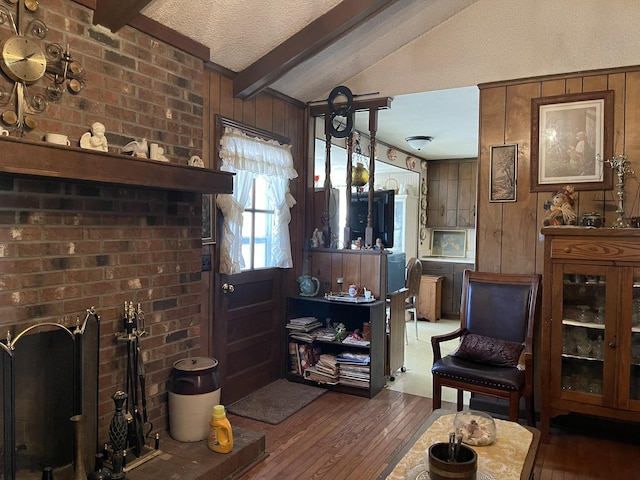 living room featuring dark wood-type flooring, wood walls, a textured ceiling, and vaulted ceiling with beams