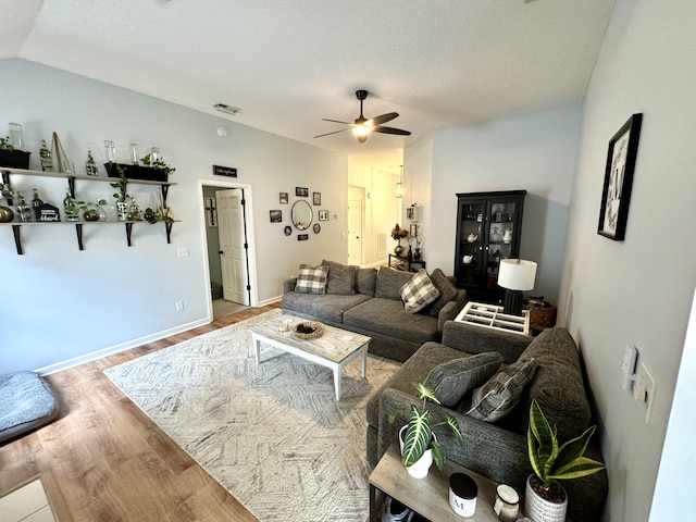 living room featuring ceiling fan, lofted ceiling, hardwood / wood-style floors, and a textured ceiling