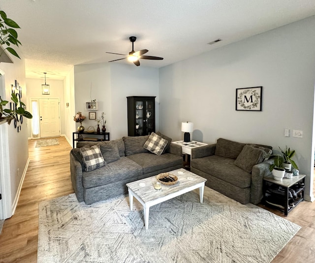 living room with a textured ceiling, light hardwood / wood-style flooring, and ceiling fan