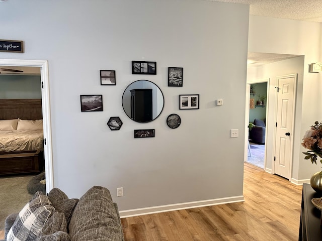 hall with light wood-type flooring and a textured ceiling