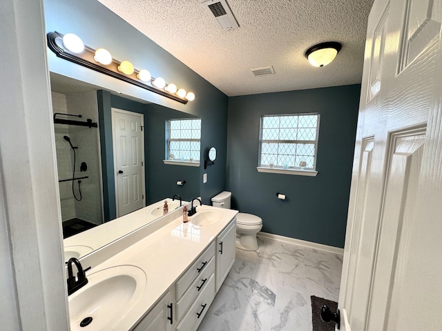 bathroom with vanity, toilet, a shower with shower door, and a textured ceiling