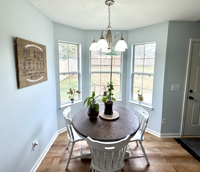 dining room with hardwood / wood-style flooring, plenty of natural light, a textured ceiling, and a chandelier