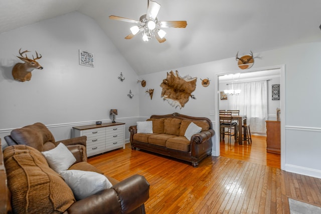 living room featuring lofted ceiling, ceiling fan with notable chandelier, and light hardwood / wood-style floors