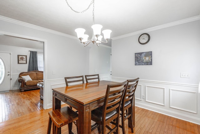 dining room with an inviting chandelier, crown molding, and light wood-type flooring