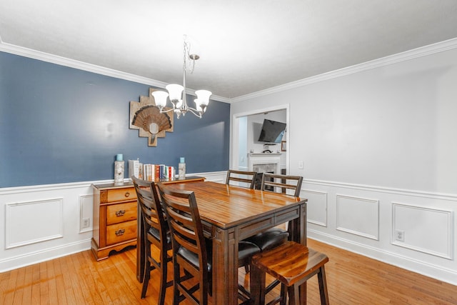 dining space featuring an inviting chandelier, crown molding, and light hardwood / wood-style floors