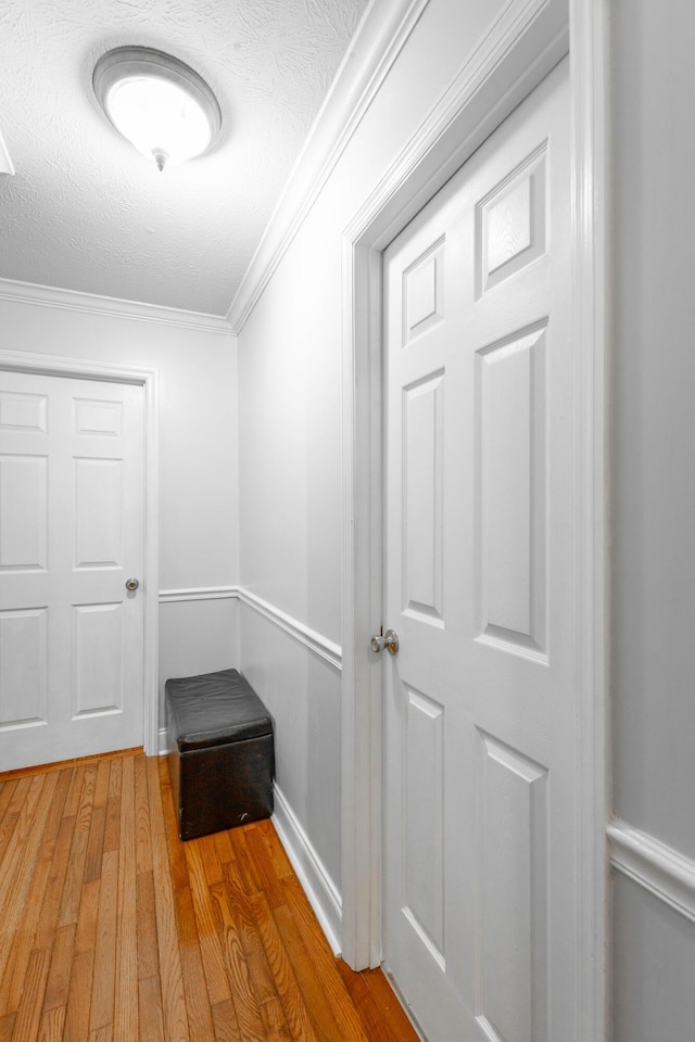 hall featuring wood-type flooring, ornamental molding, and a textured ceiling