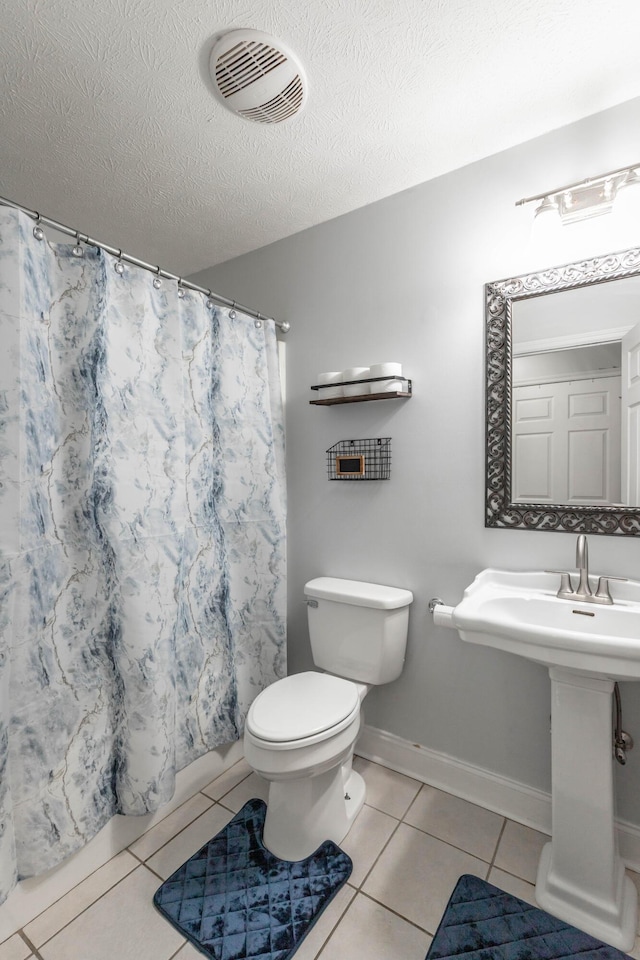 bathroom featuring tile patterned flooring, toilet, a textured ceiling, and walk in shower