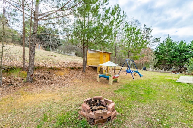 view of yard featuring a playground and an outdoor fire pit