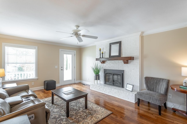 living room with ornamental molding, hardwood / wood-style floors, and a brick fireplace