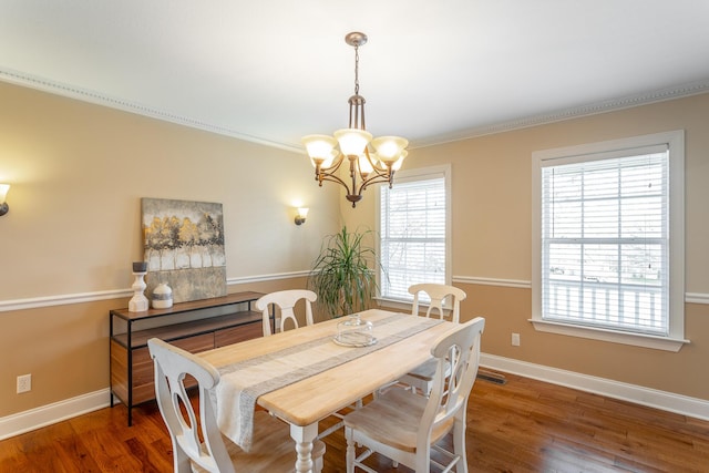 dining space with ornamental molding, dark hardwood / wood-style floors, and a chandelier