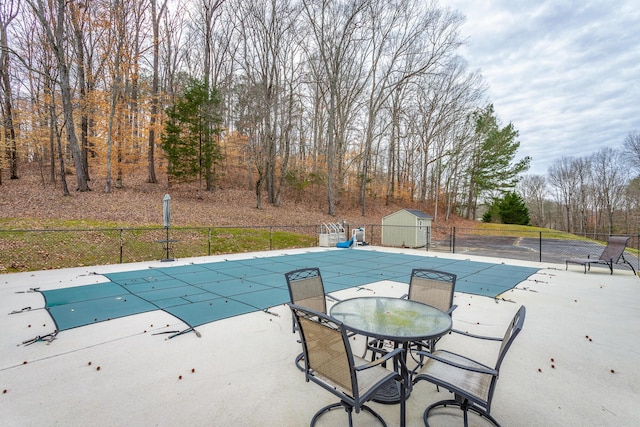 view of swimming pool featuring a shed and a patio