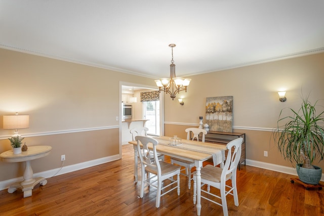 dining area with crown molding, hardwood / wood-style flooring, and a chandelier