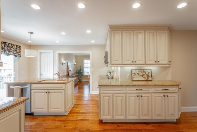 kitchen with pendant lighting, light stone countertops, stainless steel dishwasher, and cream cabinetry