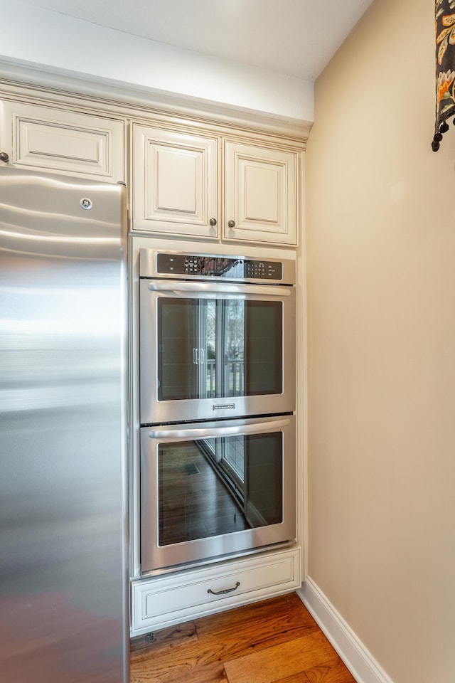 kitchen with light hardwood / wood-style flooring, cream cabinetry, and appliances with stainless steel finishes