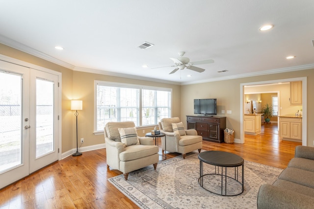 living room with crown molding, ceiling fan, light hardwood / wood-style floors, and french doors