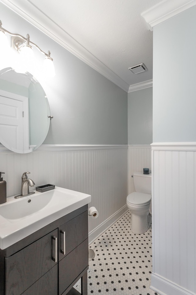 bathroom with ornamental molding, vanity, and toilet