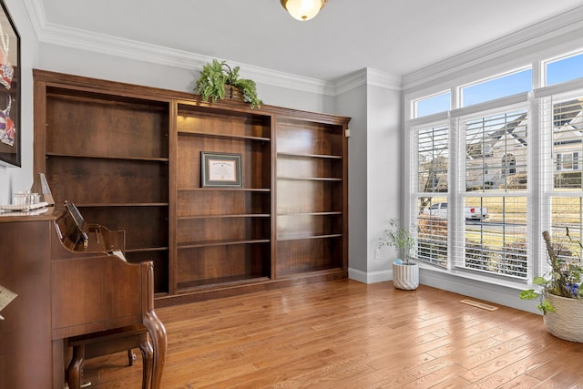 office area with ornamental molding, a wealth of natural light, and light hardwood / wood-style floors