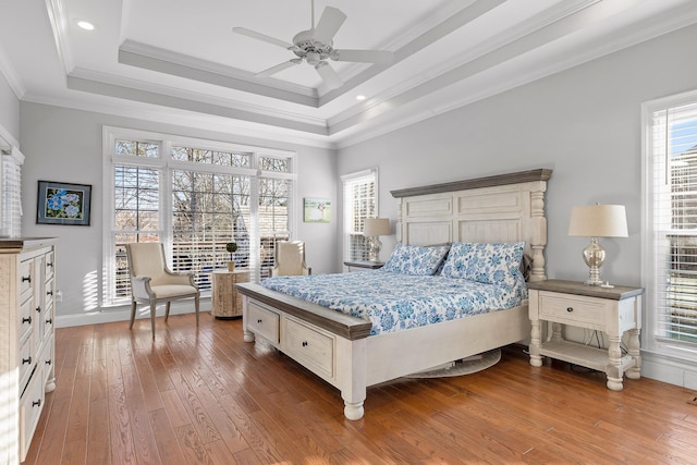 bedroom with hardwood / wood-style floors, crown molding, access to outside, and a raised ceiling