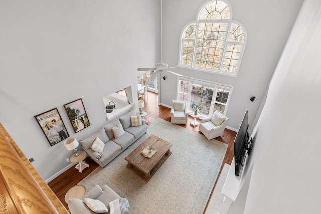 living room featuring a towering ceiling, ceiling fan, and hardwood / wood-style flooring