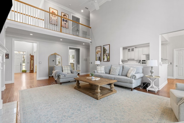 living room with crown molding, light hardwood / wood-style flooring, and a towering ceiling