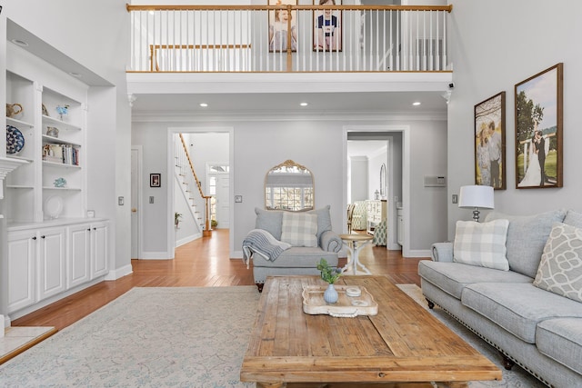 living room featuring ornamental molding, a towering ceiling, and light hardwood / wood-style flooring