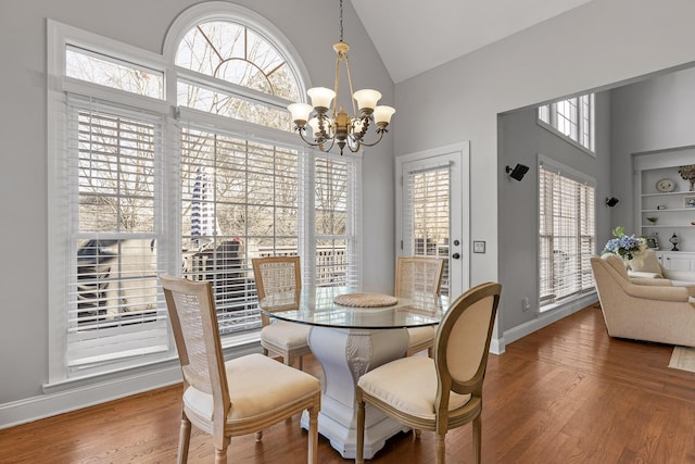 dining area featuring hardwood / wood-style flooring, high vaulted ceiling, and a notable chandelier