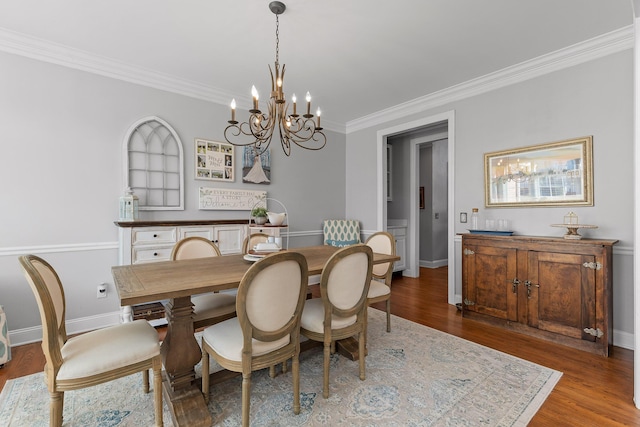 dining area featuring hardwood / wood-style flooring, crown molding, and a notable chandelier