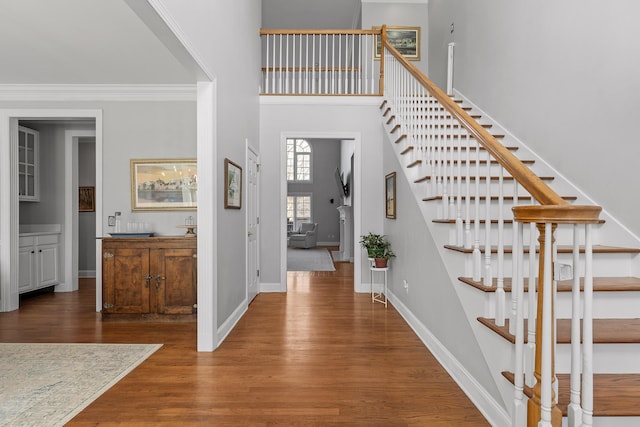 foyer entrance with a towering ceiling, ornamental molding, and dark hardwood / wood-style floors