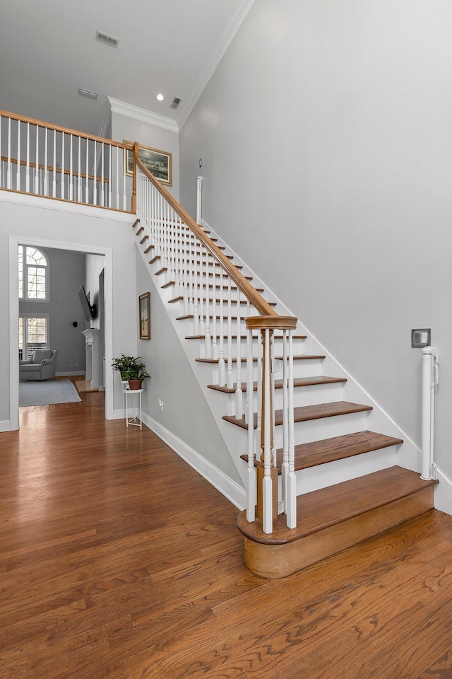 staircase with hardwood / wood-style flooring and crown molding