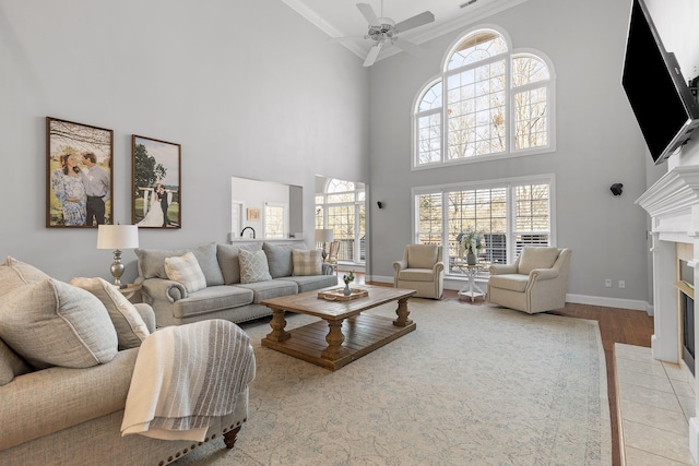 living room with ceiling fan, ornamental molding, light hardwood / wood-style floors, and a tile fireplace