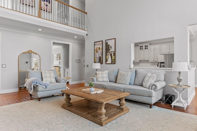 living room featuring hardwood / wood-style floors, crown molding, and a towering ceiling