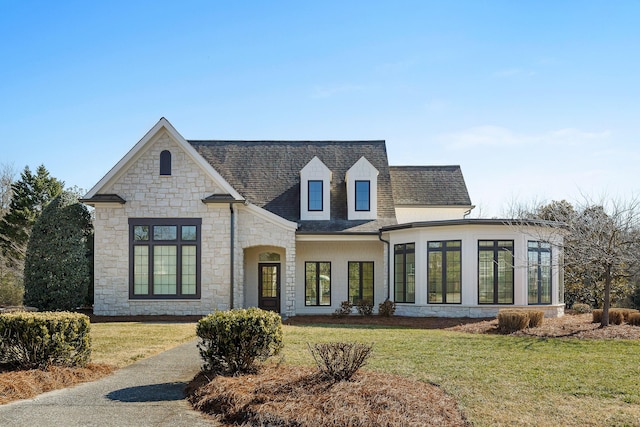 french provincial home with a front yard and a sunroom