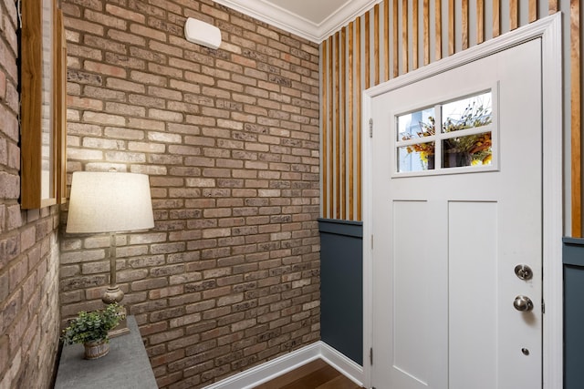 foyer entrance with crown molding and brick wall