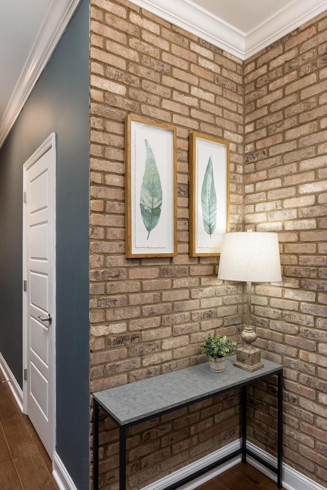 interior space featuring ornamental molding, brick wall, and dark hardwood / wood-style flooring