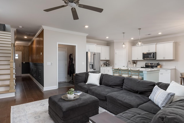 living room with crown molding, dark wood-type flooring, sink, and ceiling fan