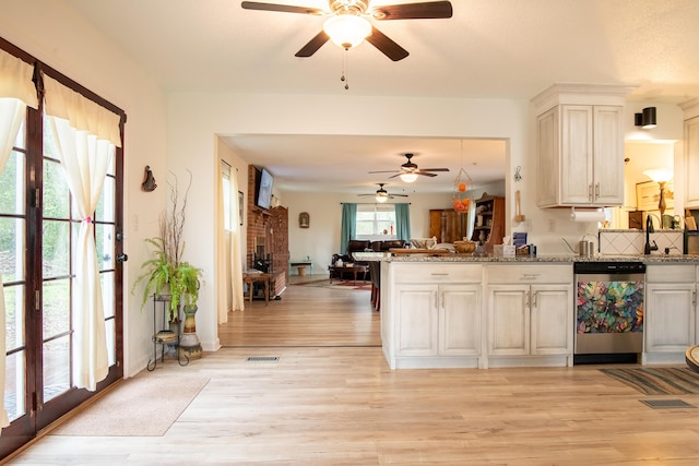 kitchen featuring a fireplace, dishwasher, light stone countertops, and light hardwood / wood-style flooring