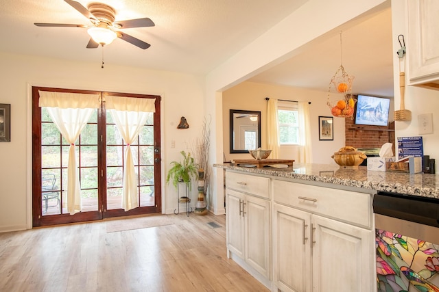 kitchen with ceiling fan, light stone counters, and light hardwood / wood-style flooring