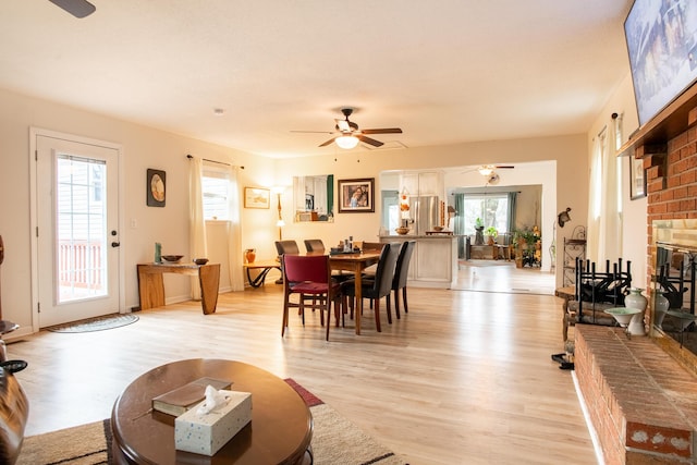 living room with ceiling fan, a fireplace, and light wood-type flooring