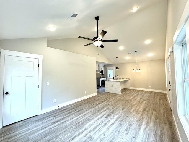 unfurnished living room with lofted ceiling, sink, wood-type flooring, and ceiling fan