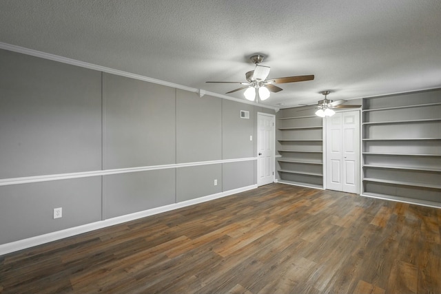 unfurnished bedroom with a textured ceiling, ornamental molding, dark hardwood / wood-style floors, two closets, and ceiling fan