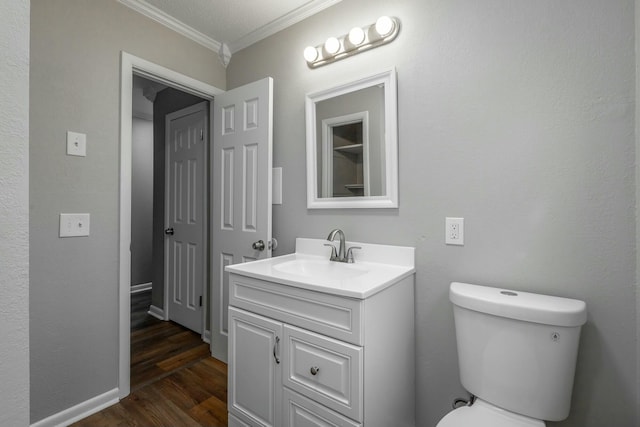 bathroom featuring ornamental molding, toilet, hardwood / wood-style floors, and vanity