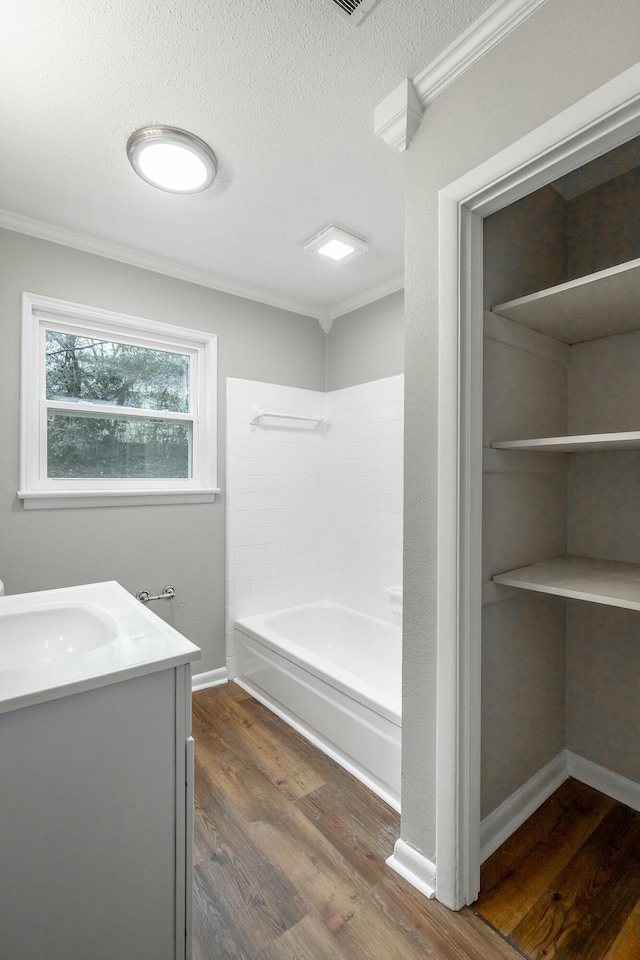 bathroom featuring ornamental molding, hardwood / wood-style floors, vanity, and a textured ceiling