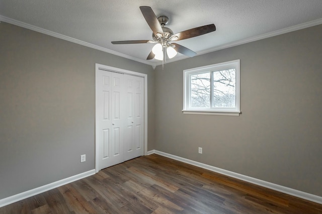 unfurnished bedroom with crown molding, dark wood-type flooring, a textured ceiling, and a closet