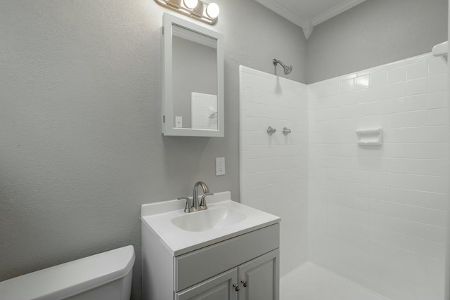 bathroom with ornamental molding, vanity, toilet, and a tile shower